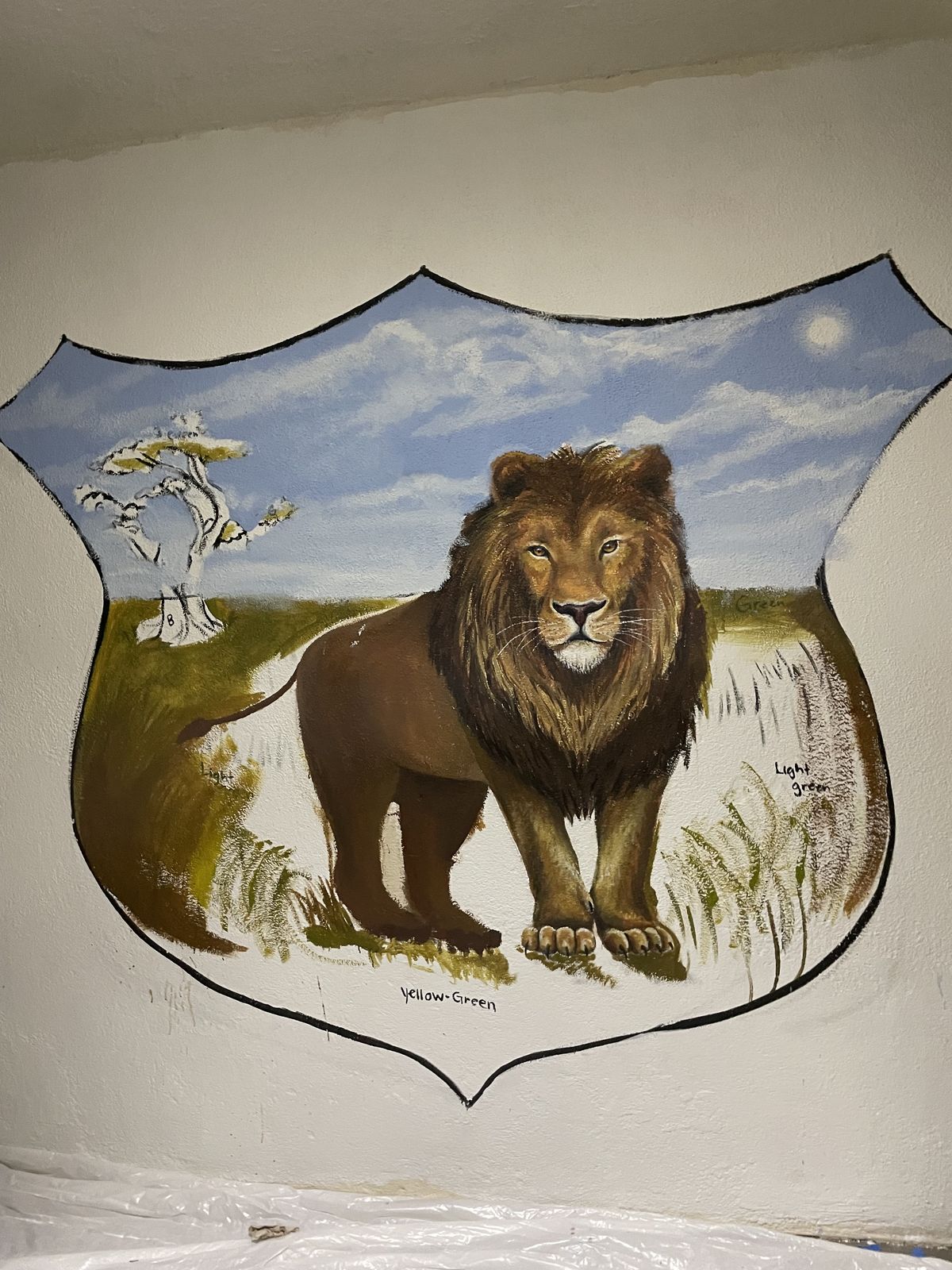 Students painting a guided lion mural alongside Mariah